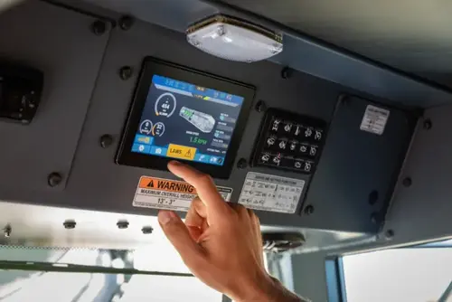 A driver presses the Light Axle Warning System icon on the Oshkosh S-Series in-cab digital touchscreen display.